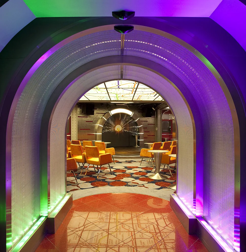 Modern entertainment lounge with illuminated archway, colorful lighting, and contemporary seating area.