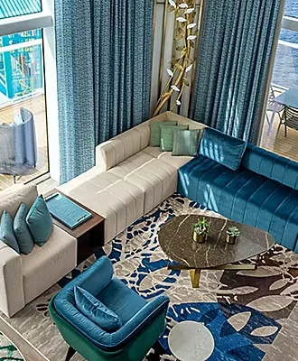 Modern hotel loft suite with blue sectional sofa, marble coffee table, and stylish contemporary décor.
