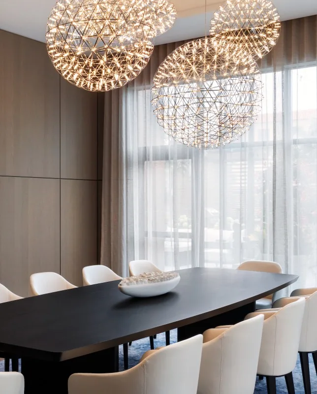 Modern dining room with black table, white chairs, and spherical pendant chandeliers.