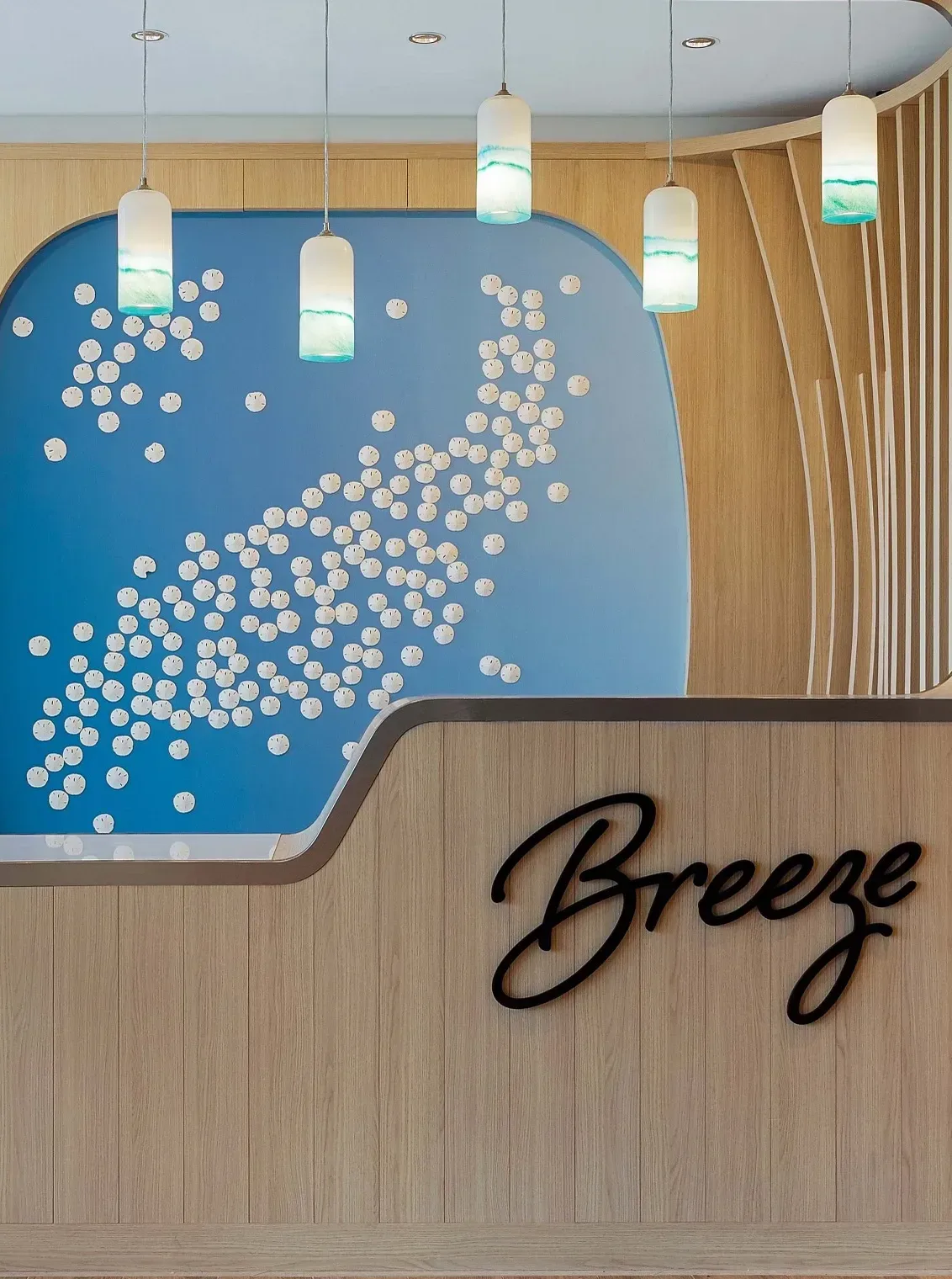 Modern reception desk with blue feature wall, pendant lights, and coastal-inspired interior design.