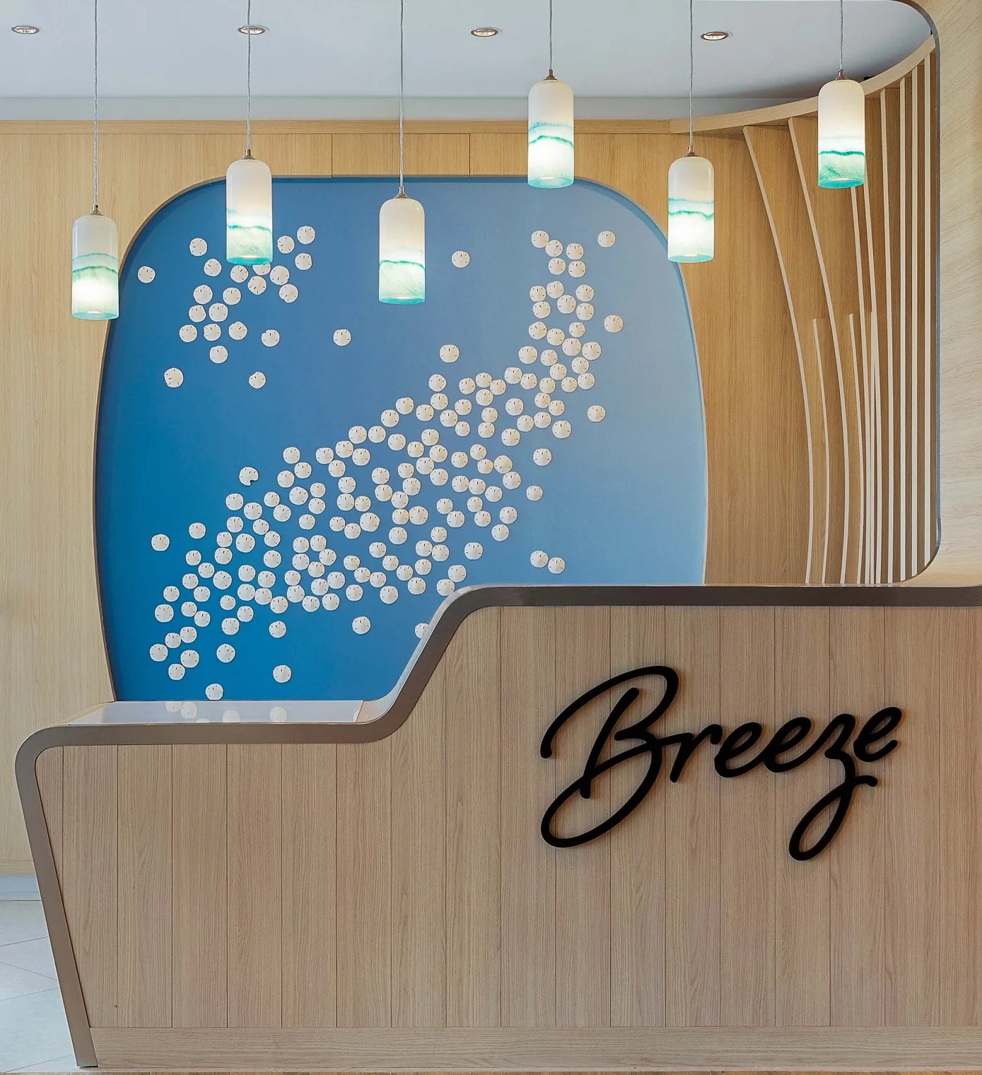 Modern reception desk with blue feature wall, pendant lights, and coastal-inspired interior design.