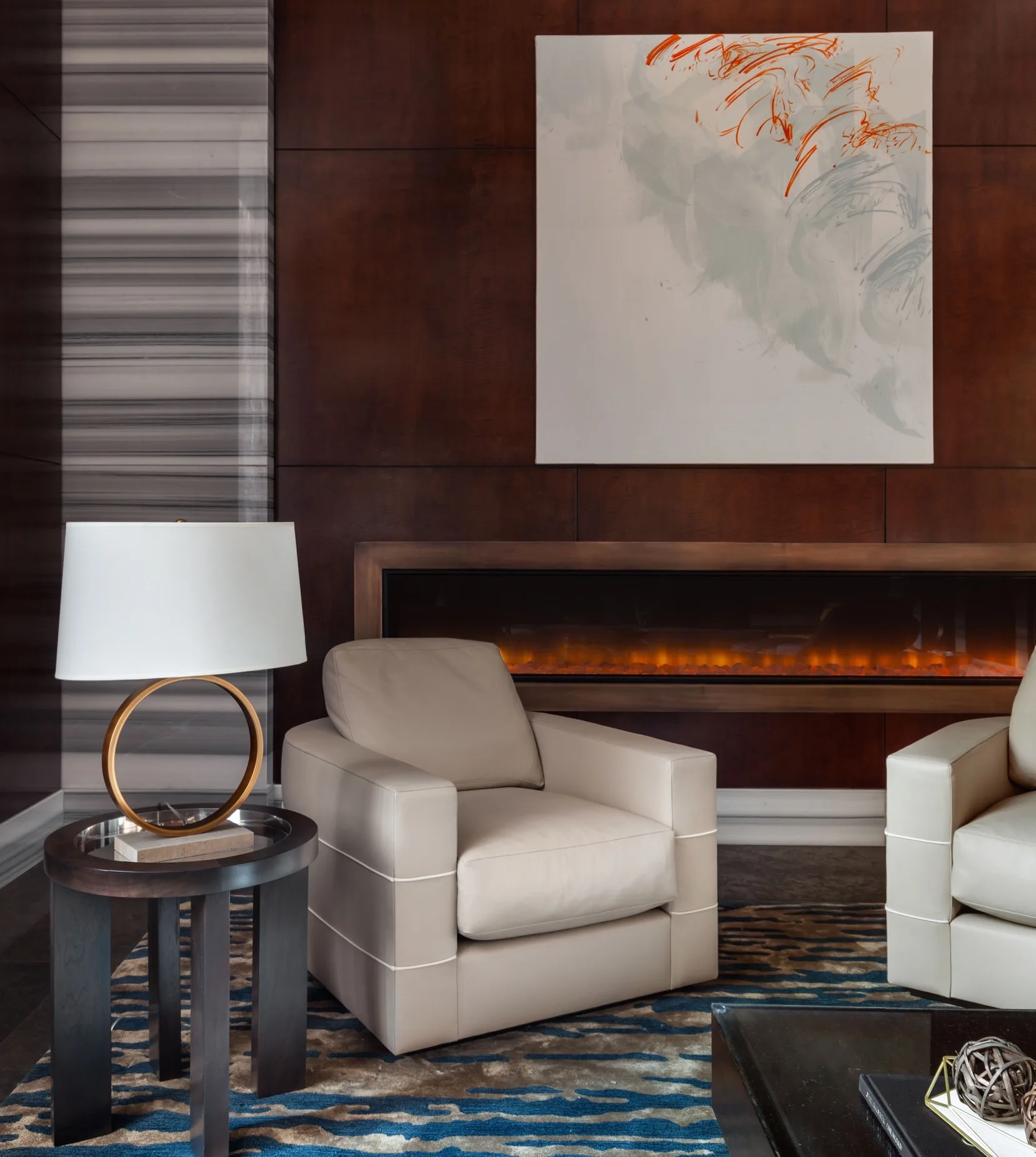 Modern hotel lobby with cream leather chairs, a linear fireplace, abstract wall art, and warm wood paneling.