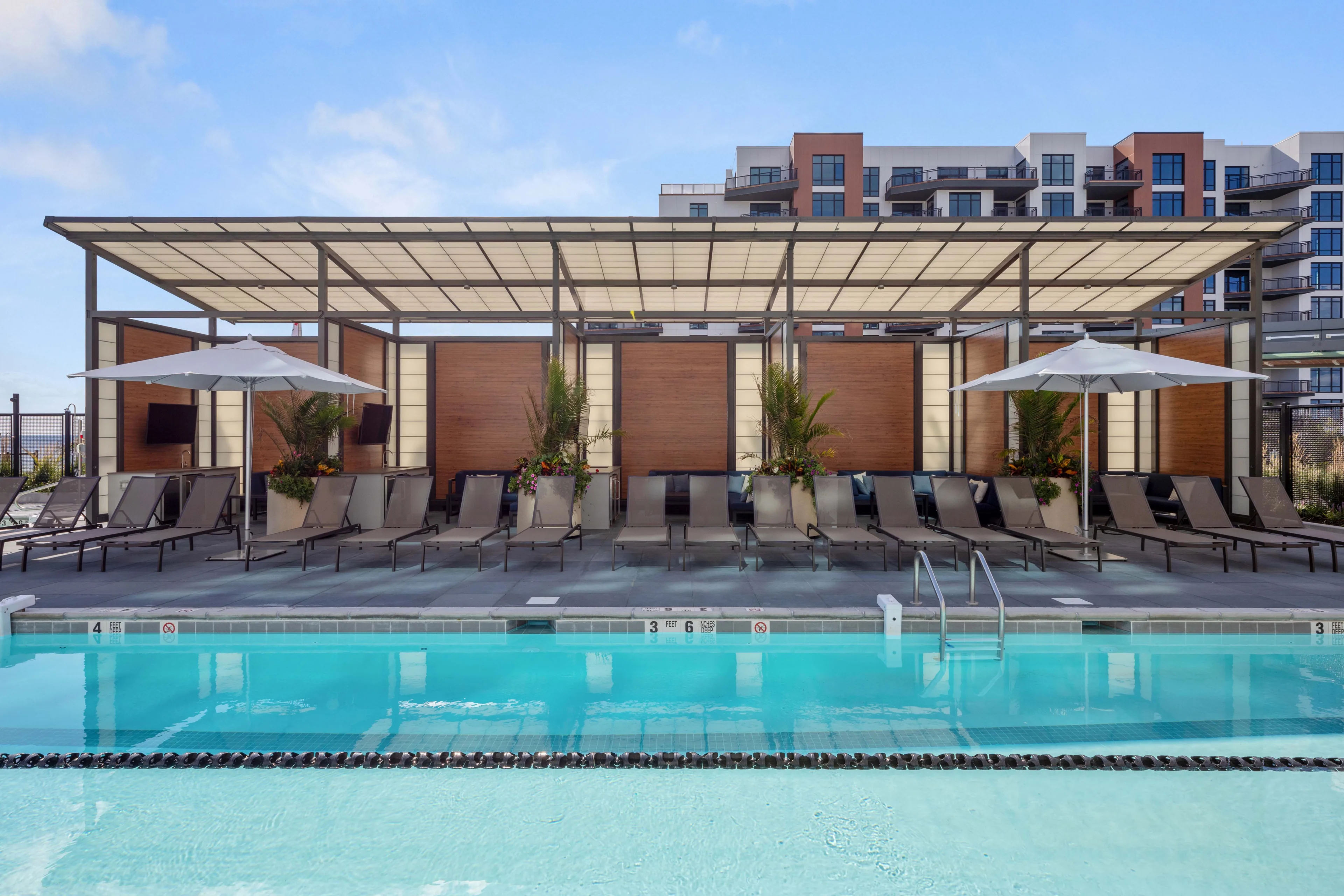 Outdoor apartment pool with lounge chairs and shaded cabanas