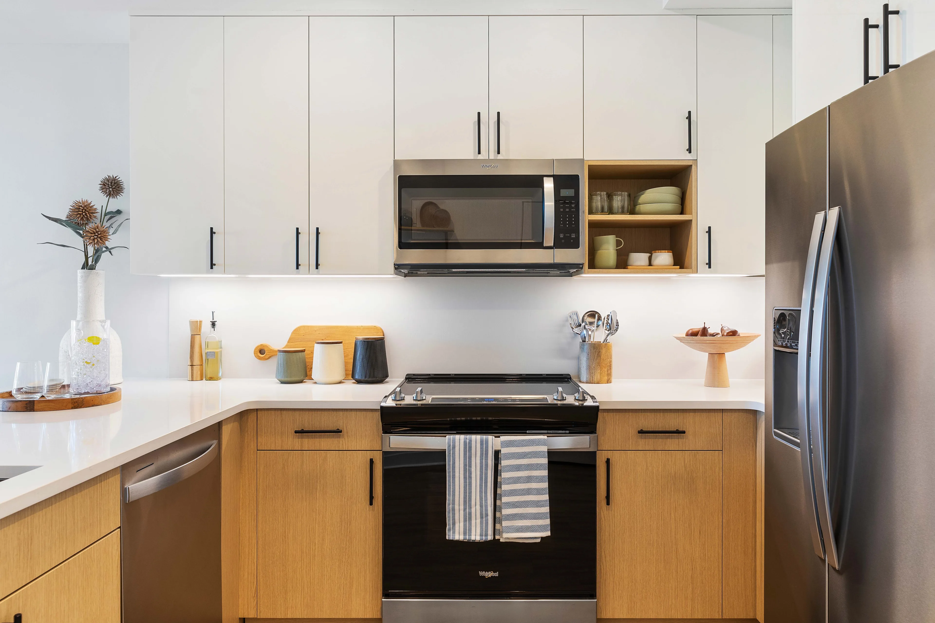 Modern apartment kitchen with wood cabinetry and stainless steel appliances