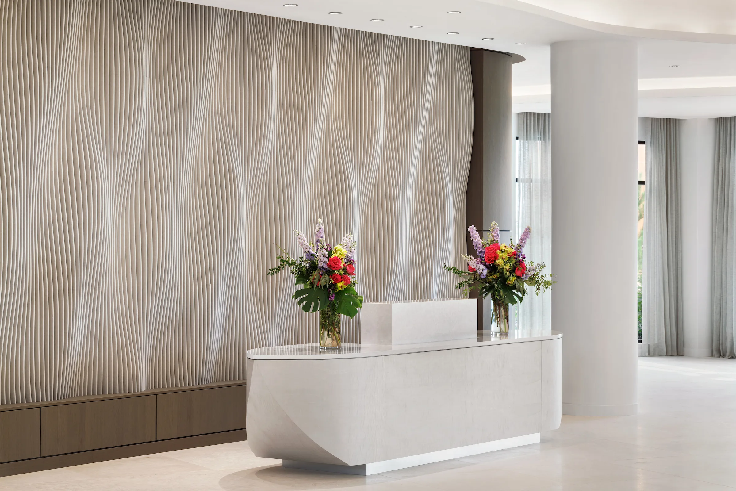 Modern reception desk with textured feature wall and floral arrangements
