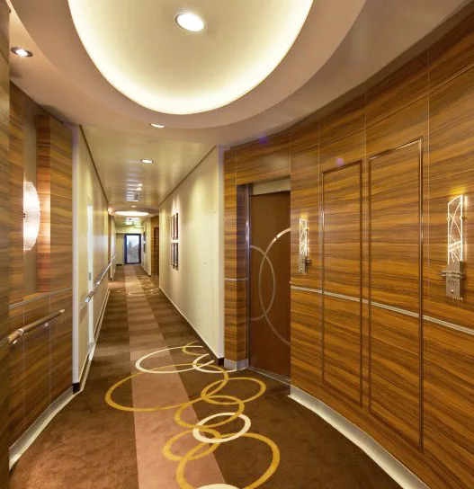Luxury hotel corridor with warm wood paneling, circular ceiling lighting and patterned carpet