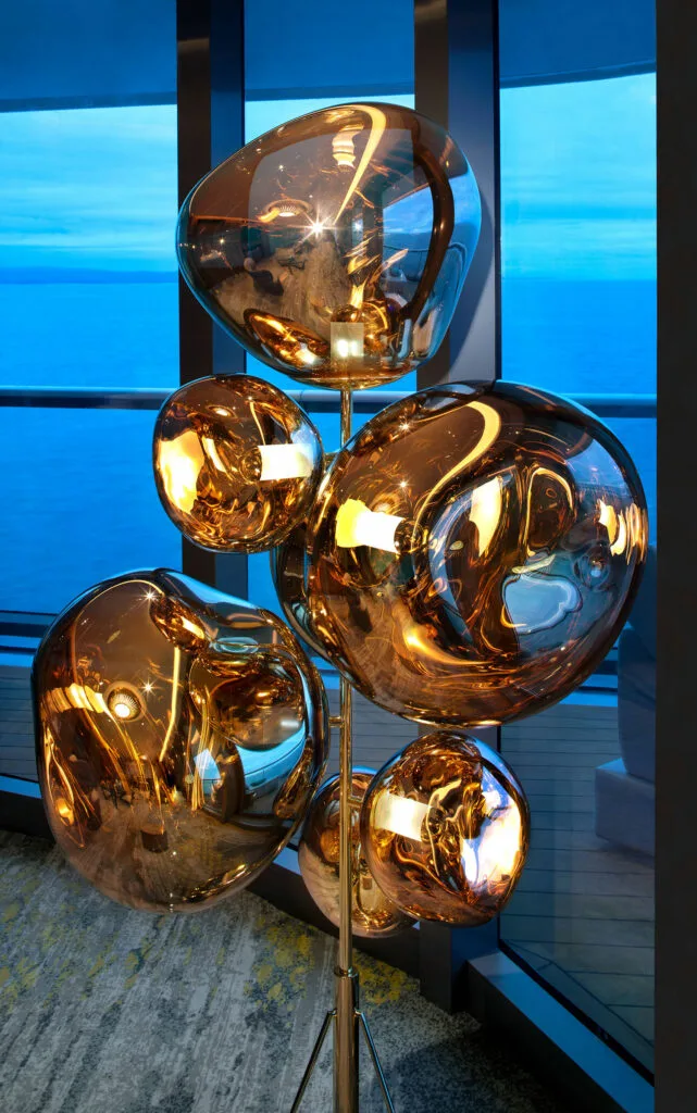 Gold sculptural lights beside ocean-facing windows.