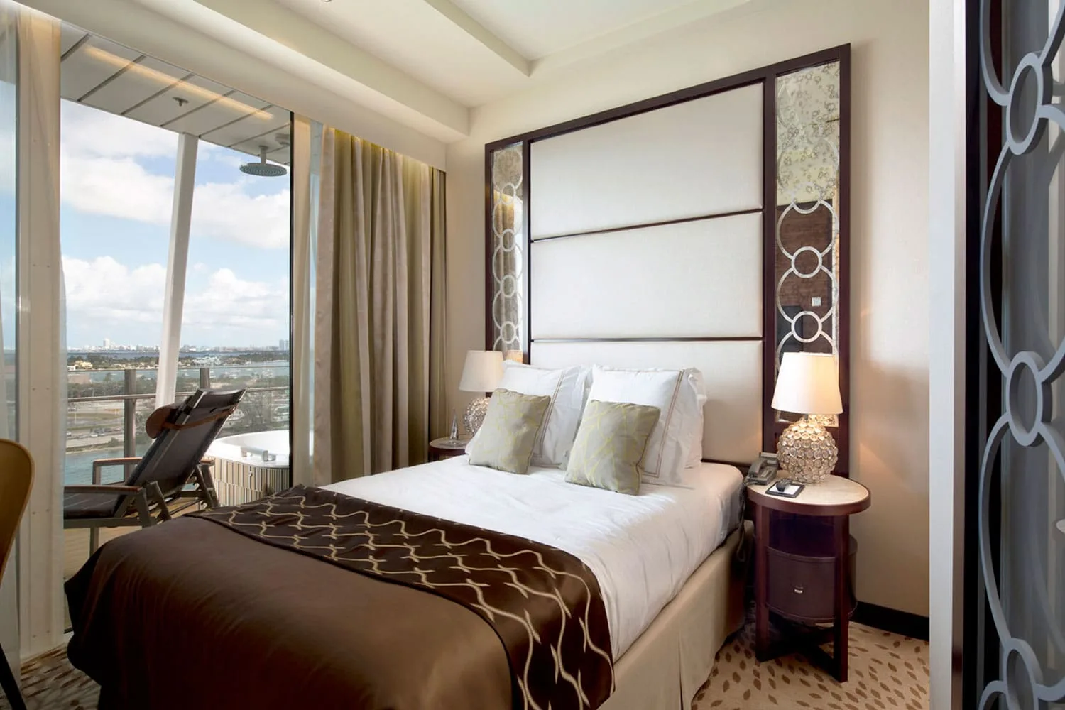 Luxury hotel bedroom with upholstered headboard, contemporary furnishings and private balcony