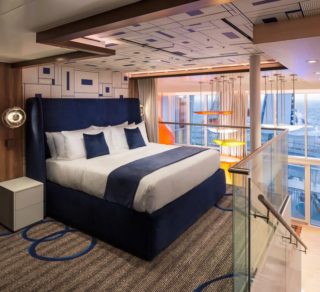Upper-level family suite bedroom with blue bed and glass railing.