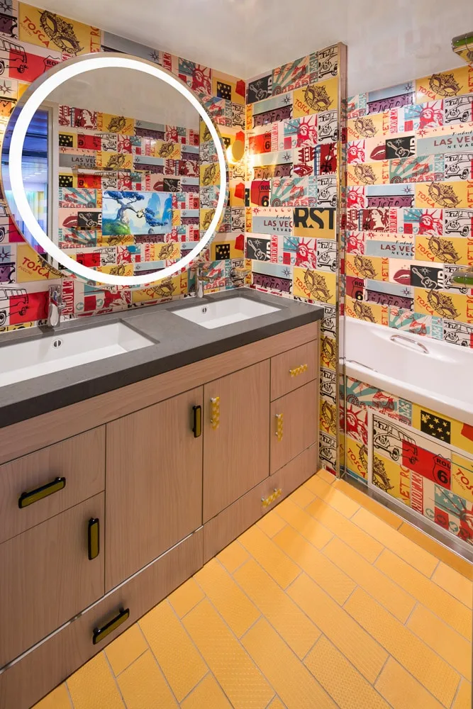 Kids’ bathroom with pop-art walls and round illuminated mirror.